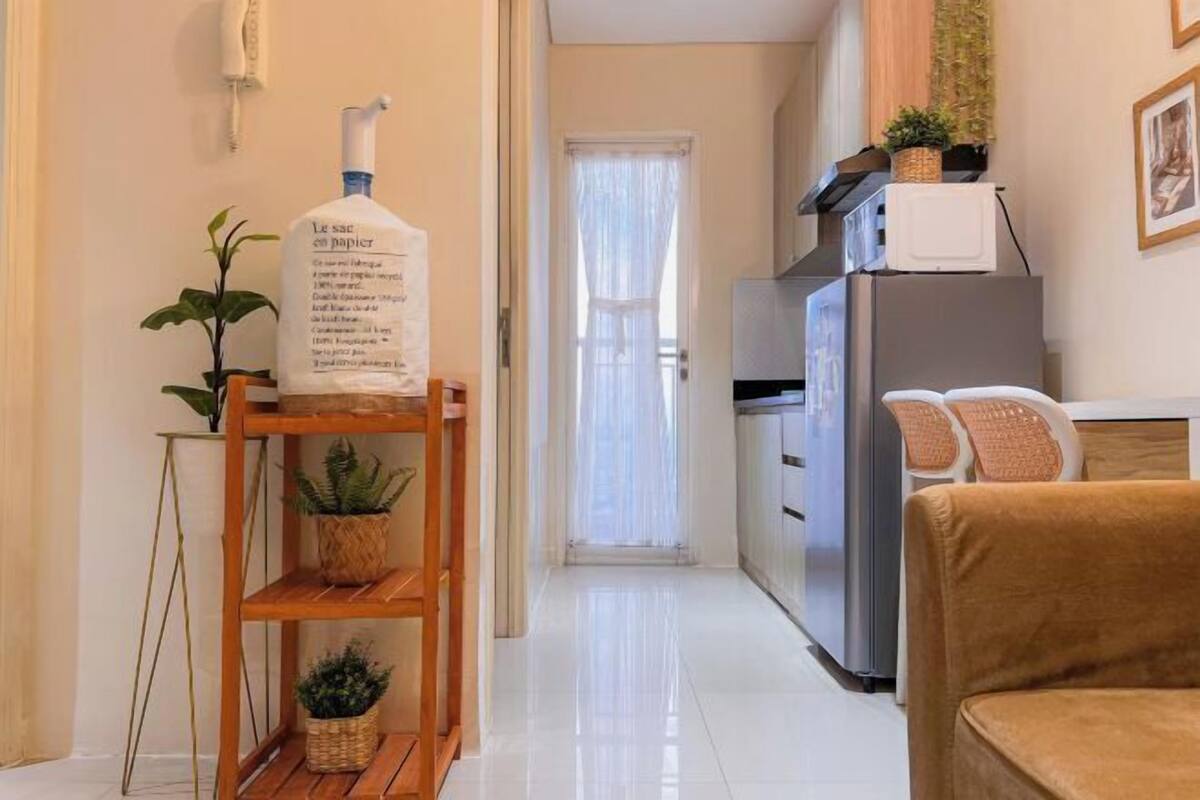 Een moderne keuken met een koelkast, magnetron en een houten plank met planten.