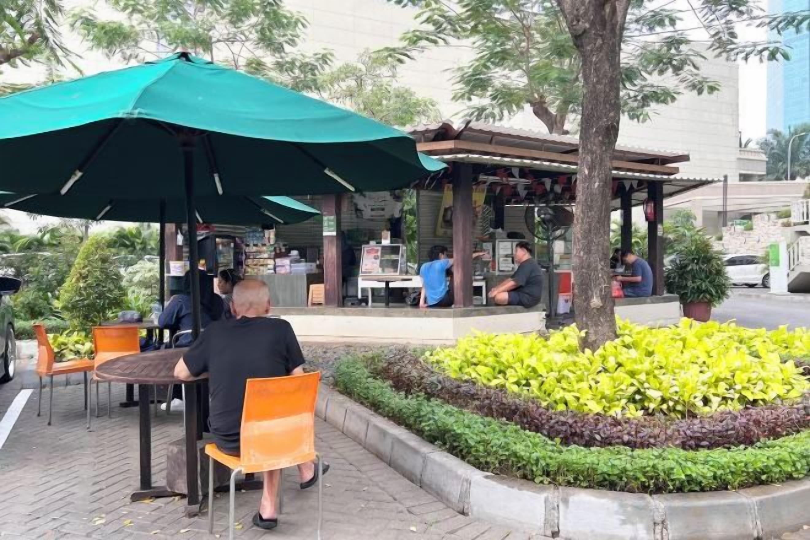 An outdoor seating area with tables and chairs, a covered section, and a landscaped garden.