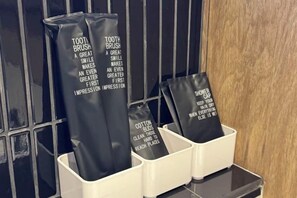 A set of toiletries in a hotel bathroom, including toothbrushes, cotton buds, and a shower cap.