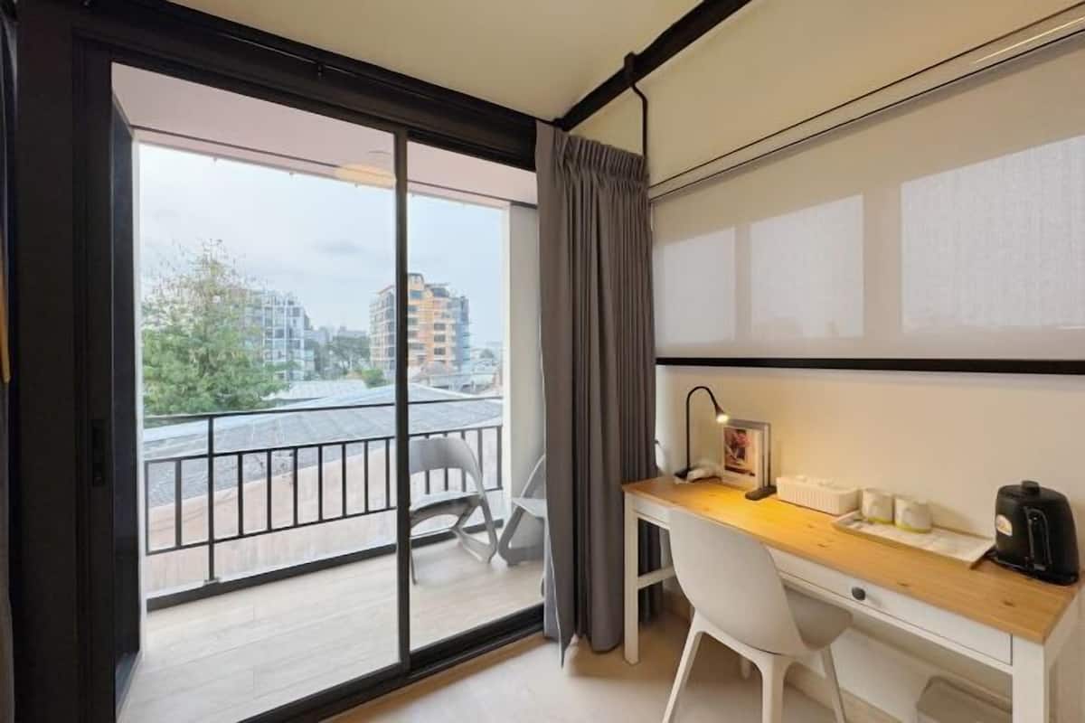 Een moderne hotelkamer met een balkon, een bureau, een stoel en een koffieapparaat.