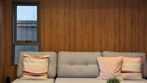 Een bank met drie kussens tegen een houten wand.