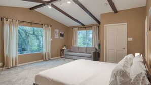 A bedroom with a large bed, a sofa, and a window with curtains. - Sleeps 18! Game Room, Deck w/ Firepit, 5BDR, Casita | Cedar & Stone by AvantStay (Austin)