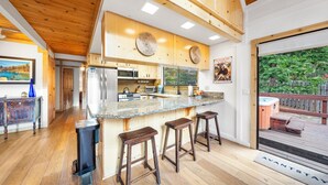 Eine moderne Küche mit Holzausstattung, einer Arbeitsplatte aus Granit und einem großen Fenster mit Blick auf eine Terrasse.