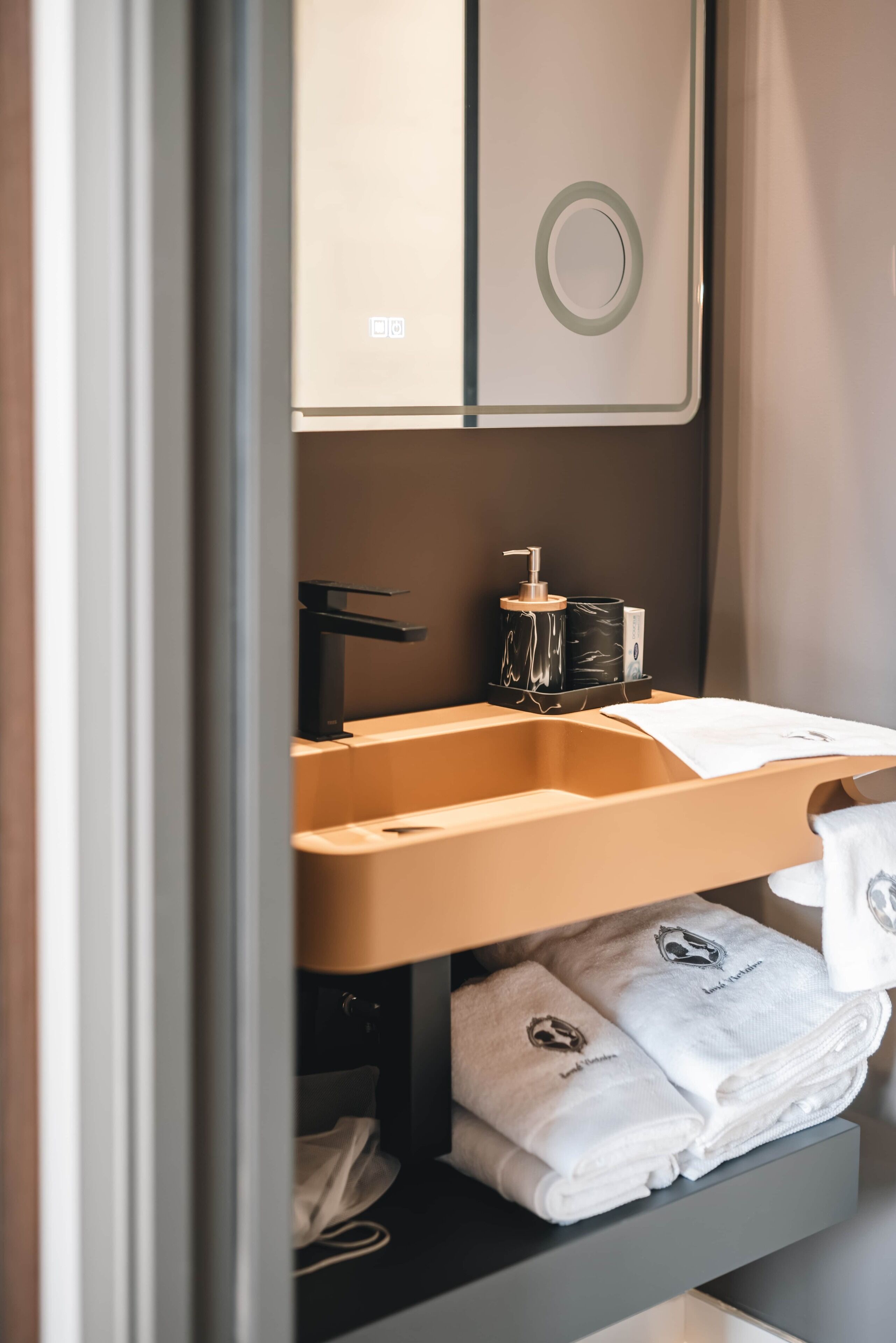 Een kleine badkamer met een wastafel, handdoekhouder en toiletartikelen.