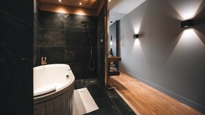 A modern bathroom with a freestanding bathtub, a shower area, and a wooden floor. - Exceptional Victoire apartment (Épinal)