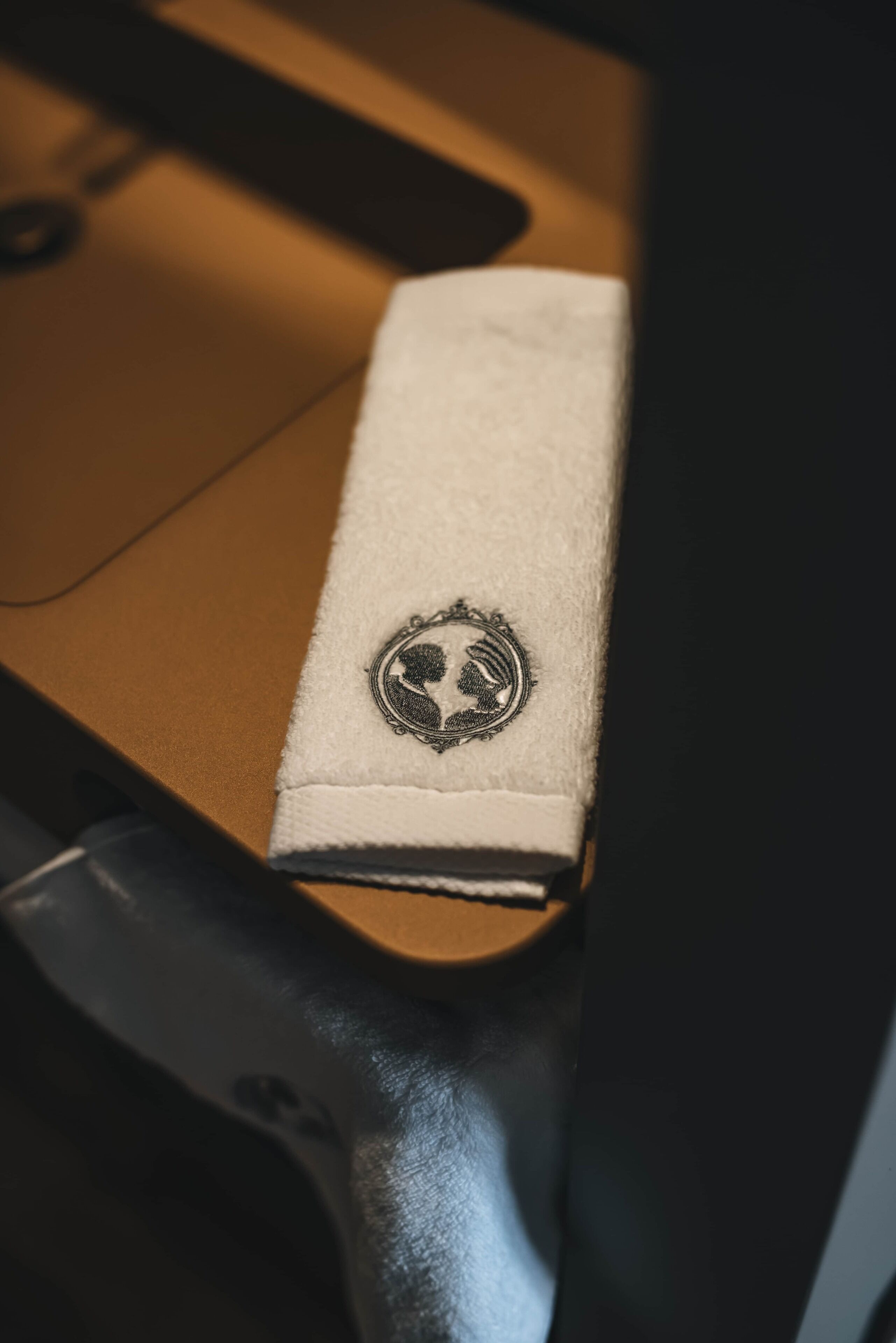 Een wit lederen tas met een cirkelvormig embleem op een houten ondergrond.