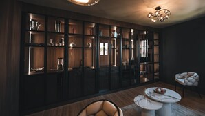 Een moderne woonkamer met een houten vloer, een marmeren salontafel, een leren fauteuil en een inbouwkast met diverse decoratieve objecten.
