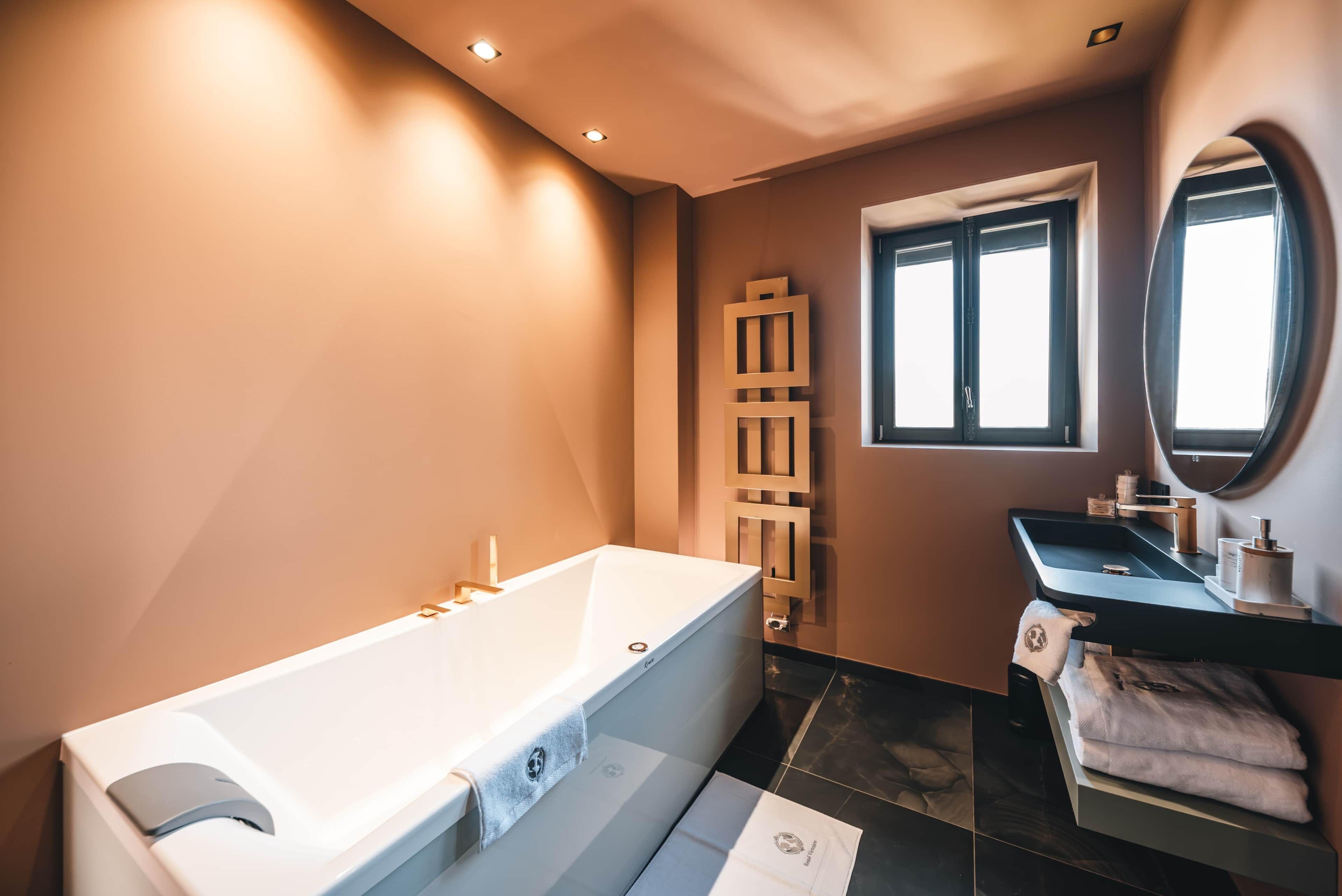 A modern bathroom with a freestanding bathtub, a vanity with a mirror, and a window providing natural light.