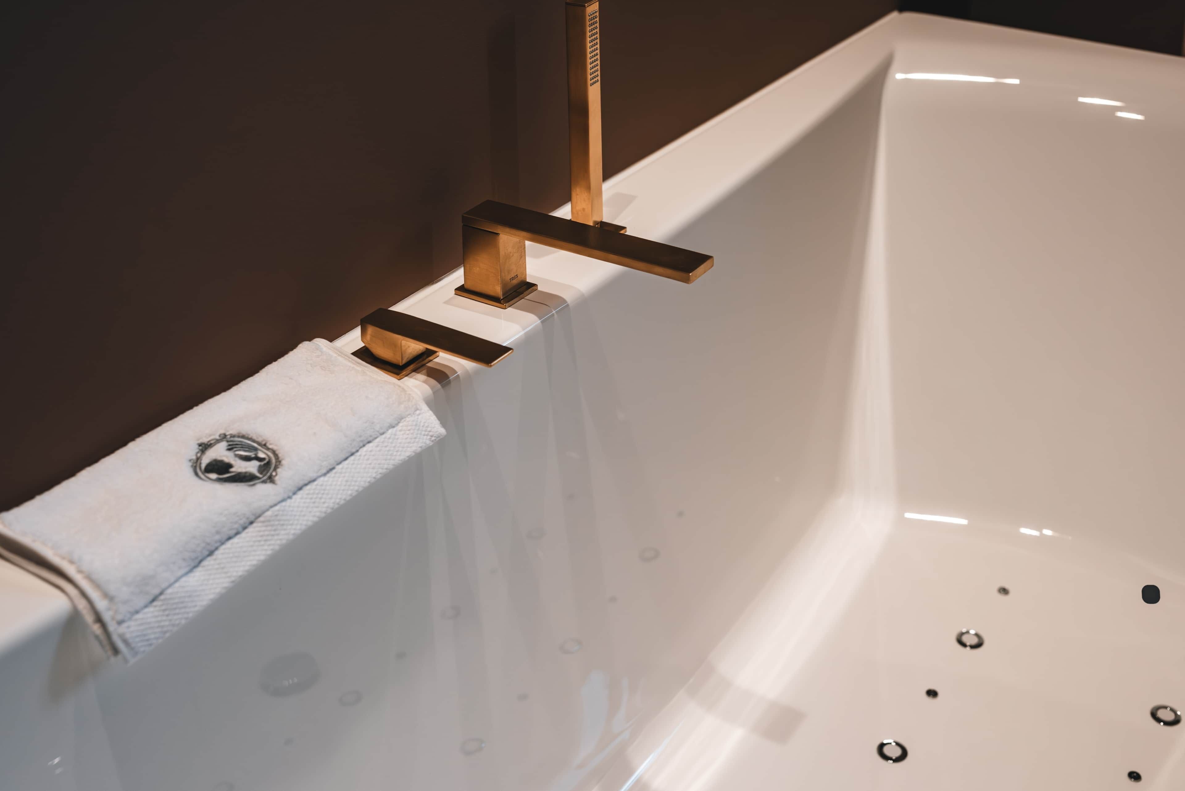 A white bathtub with a towel rack and a handheld showerhead.