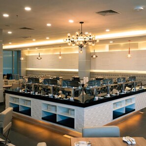A modern hotel lobby with a central island featuring buffet-style service, seating areas, and a chandelier. - Hotel Tamara Melaka (Malacca City)