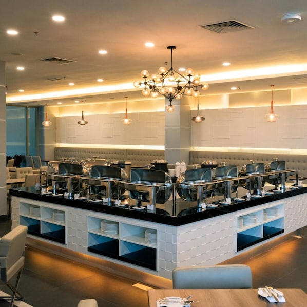 A modern hotel lobby with a central island featuring buffet-style service, seating areas, and a chandelier. - Hotel Tamara Melaka (Malacca City)
