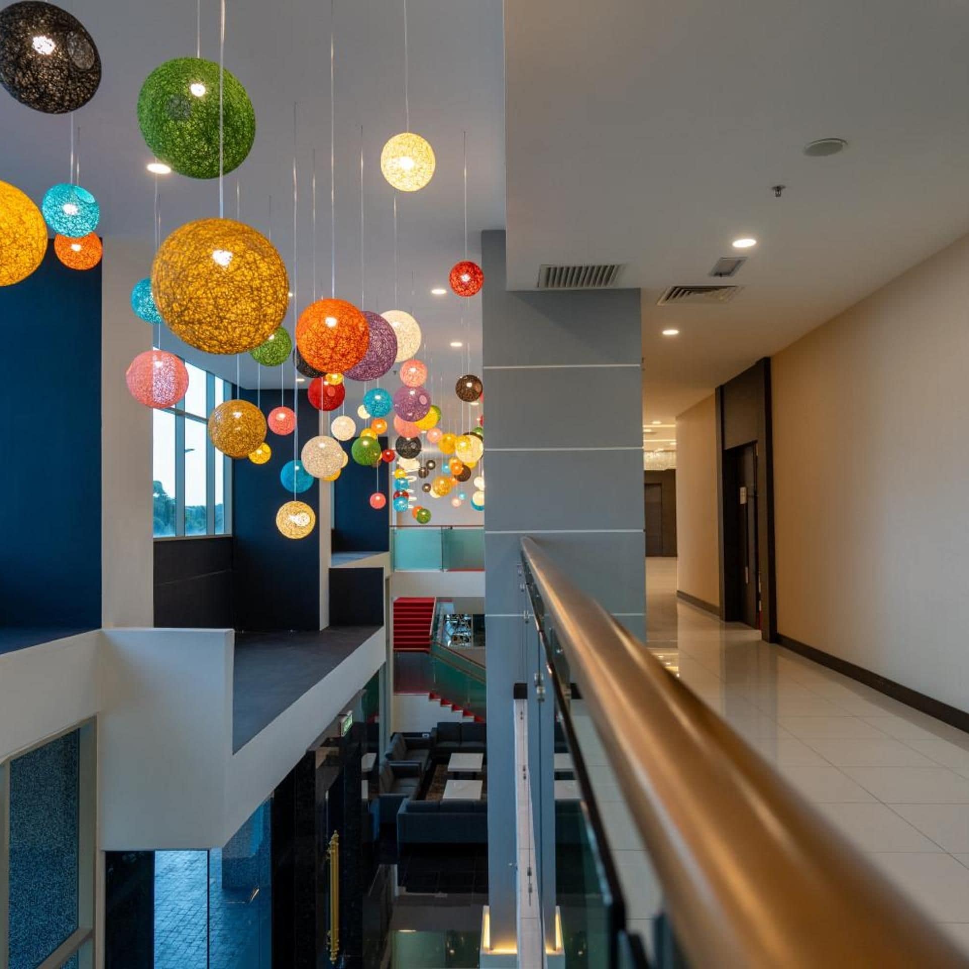 A modern interior with a glass railing, a staircase, and hanging spherical lights.