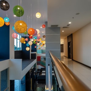 A modern interior with a glass railing, a staircase, and hanging spherical lights. - Hotel Tamara Melaka (Malacca City)