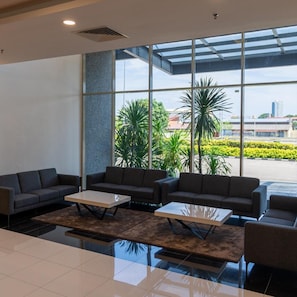 A spacious lobby with a large glass wall, modern furniture, and a view of greenery and buildings outside. - Hotel Tamara Melaka (Malacca City)