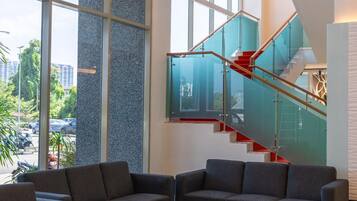 A modern interior with a staircase, large windows, and seating area.