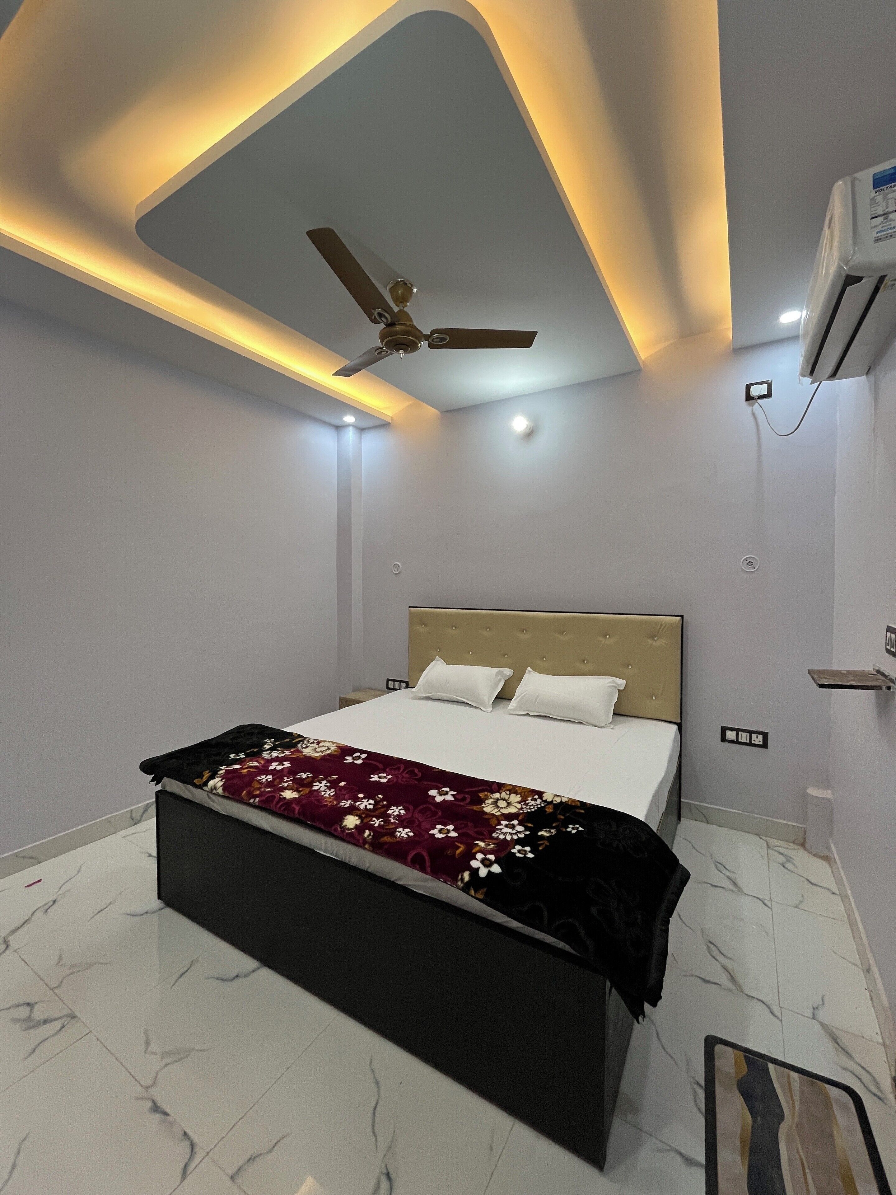 Une chambre moderne équipée d’un lit, d’un ventilateur de plafond, d’un éclairage encastré et d’un appareil de climatisation.