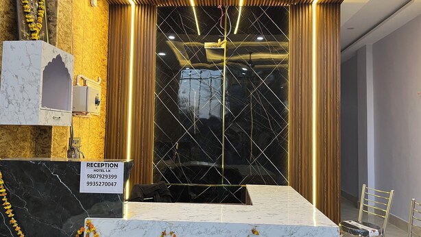 Zona de recepción de hotel con mostrador de mármol, mostrador de recepción y un gran ventanal con diseño geométrico.