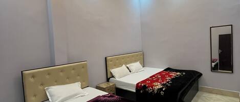 A modern bedroom with two beds, a ceiling fan, and recessed lighting.