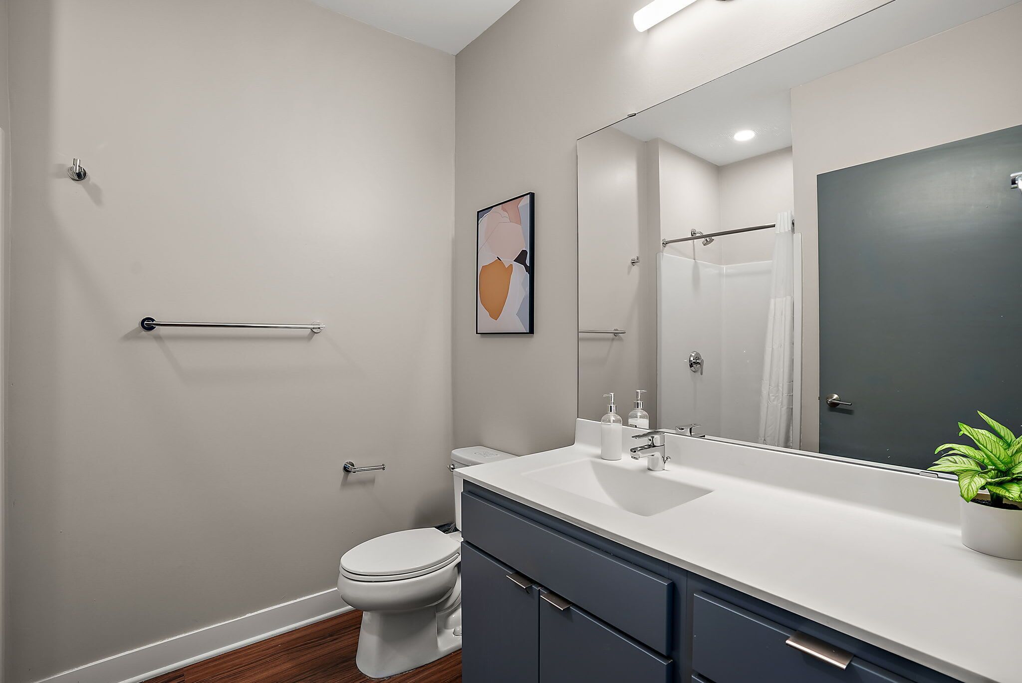 A modern bathroom with a white toilet, a vanity with a mirror, and a towel rack.
