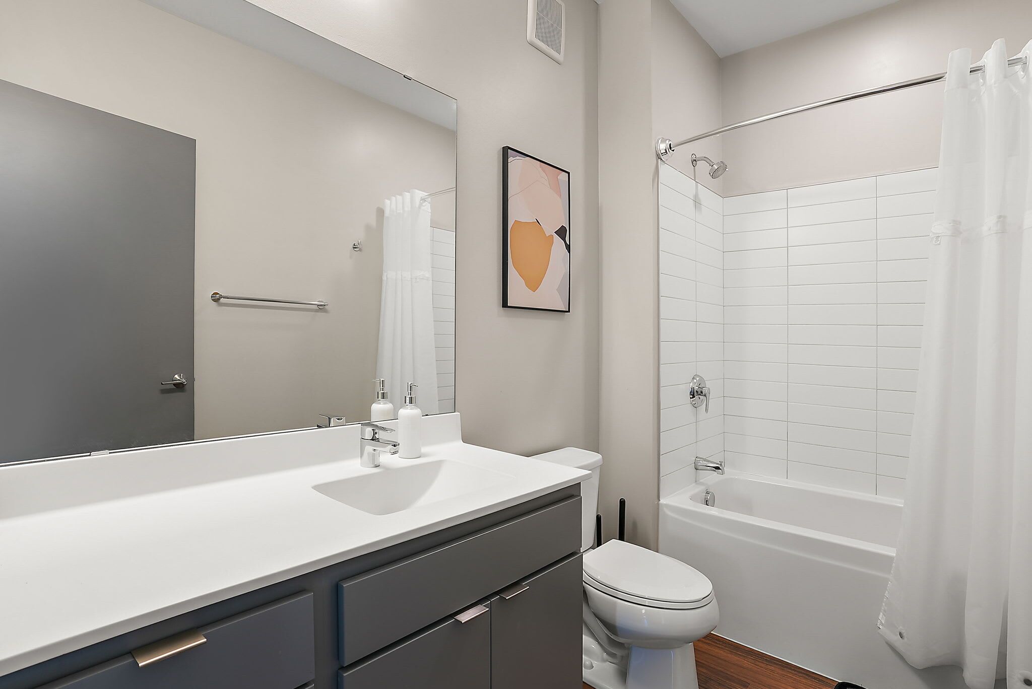 Un baño moderno con un espejo grande, lavamanos blanco y bañera.