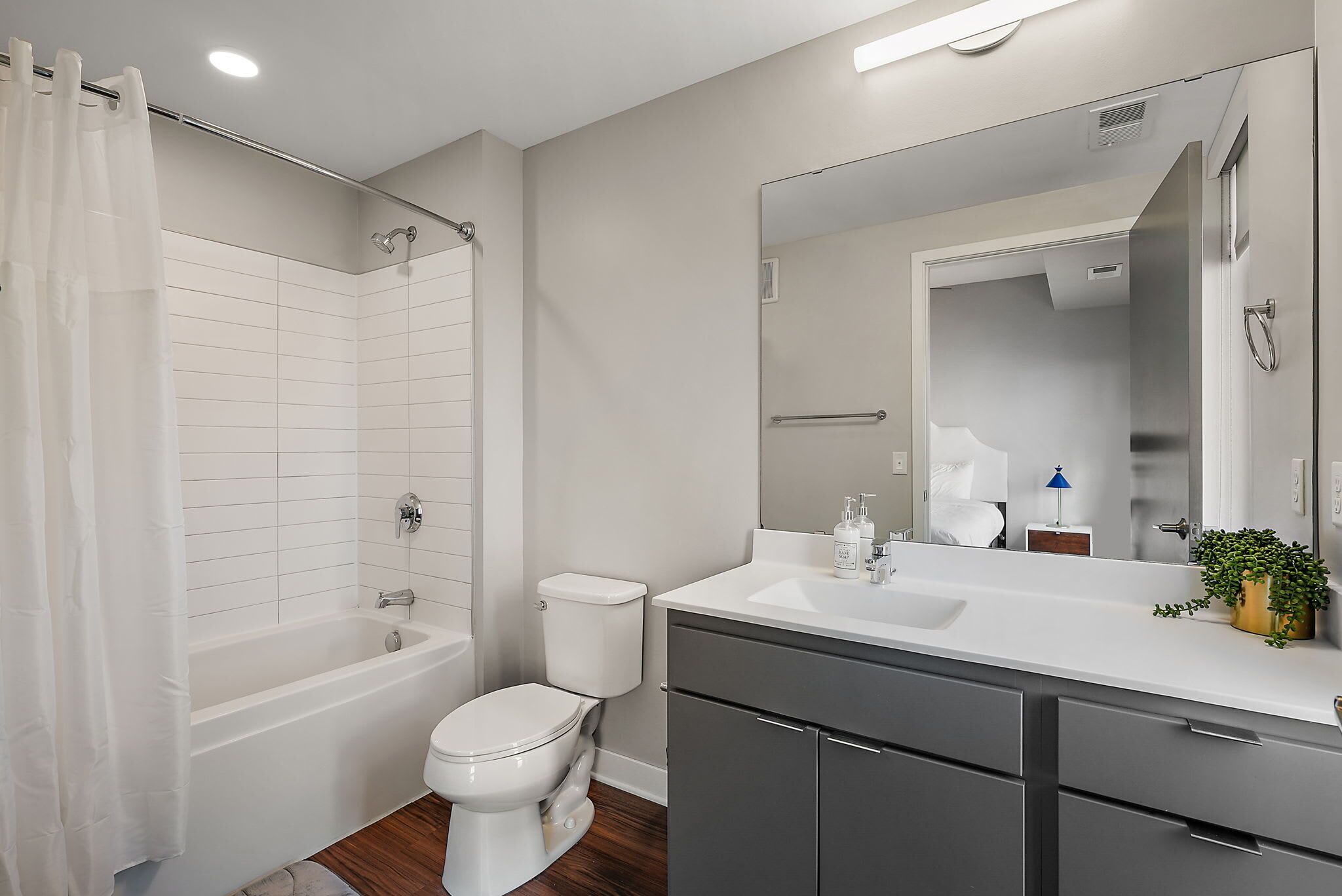 A modern bathroom with a bathtub, toilet, and vanity with a mirror.