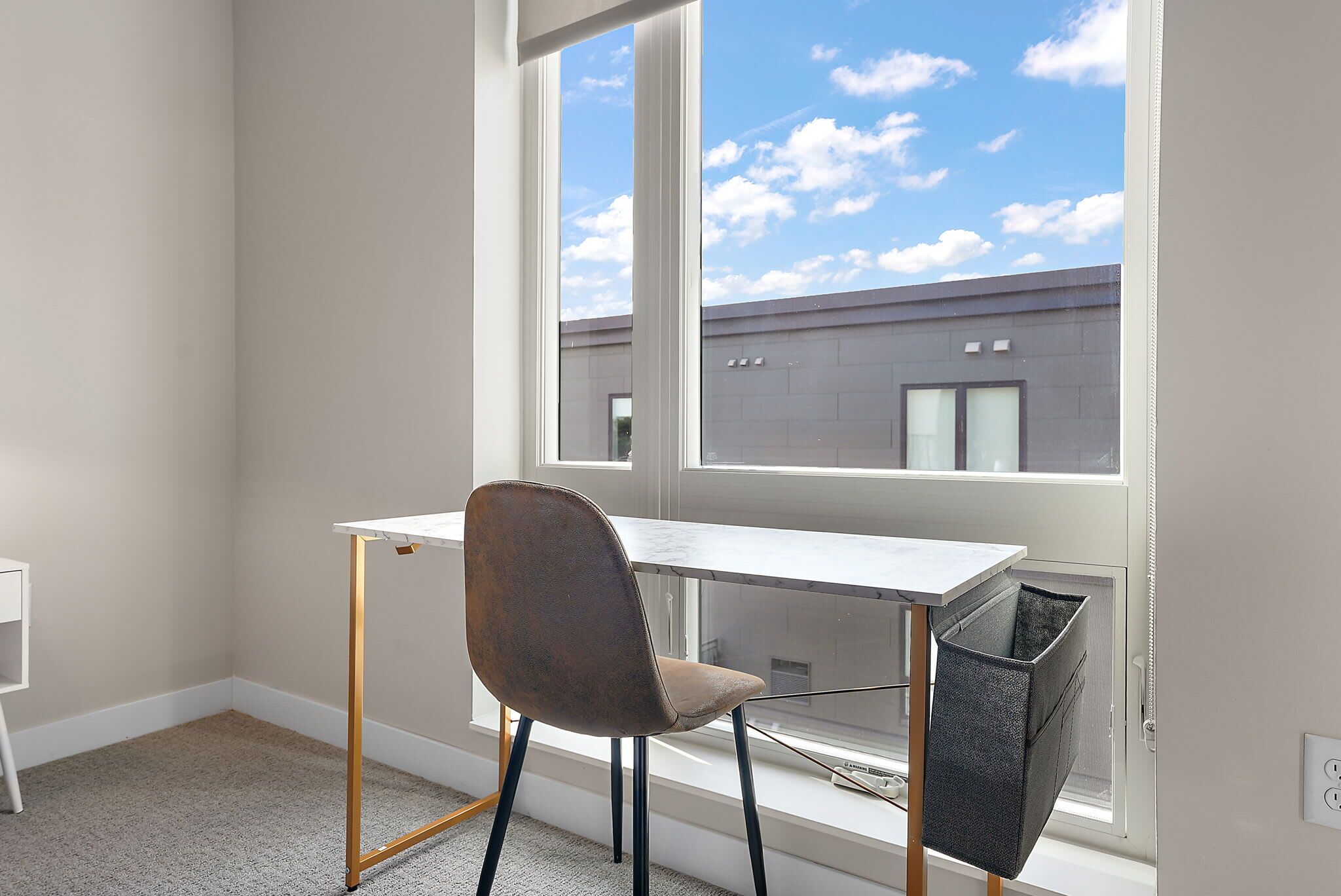 A room with a desk and chair near a window, a radiator, and a white wall.