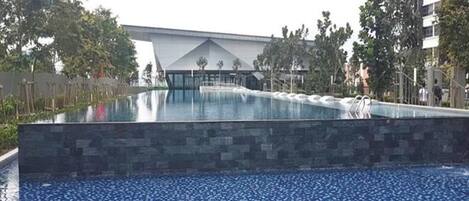 Una piscina con caída de agua, rodeada de un muro de piedra y árboles.