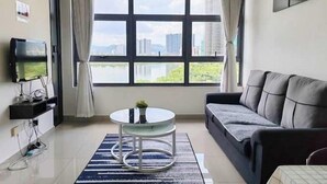 A modern living room with a large window, a sofa, a TV, and a small round table. - Lakeville KL Taman Wahyu City Centre [3Bedroom Sleep 5] (Kuala Lumpur)