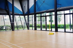 Una palestra coperta con pavimento in legno, ampie finestre e uno straccio giallo.
