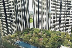 Een hoog appartementencomplex met meerdere balkons, een zwembad en veel groen eromheen.