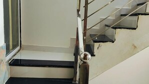 A staircase with black and white steps, a metal handrail, and a glass window to the left. - Ram Basant Hotel & Resturant (Danta Ramgarh)