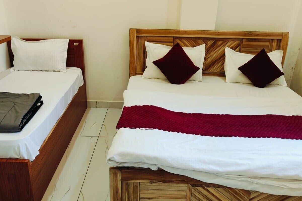 A hotel room with two beds, wooden headboards, white bedding, and a red throw blanket.