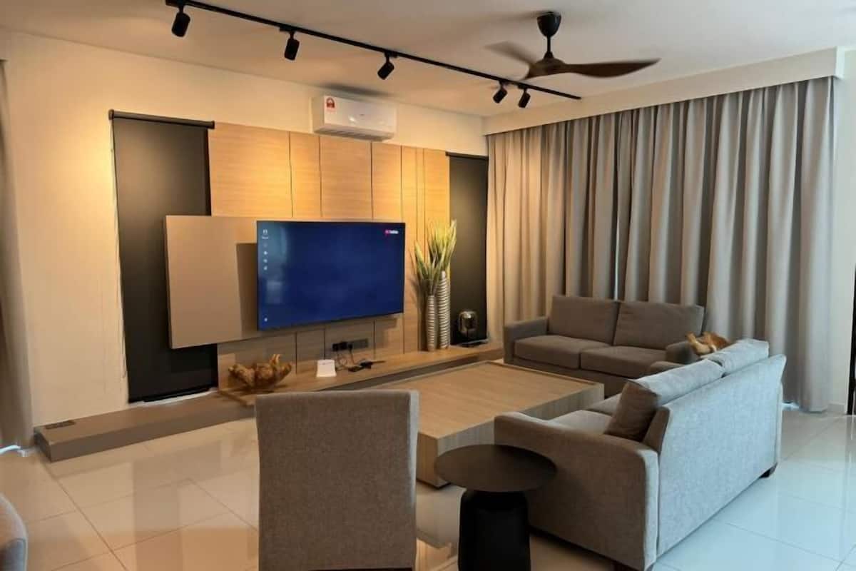 A modern living room with a flat-screen TV, a sofa, a coffee table, and a ceiling fan.