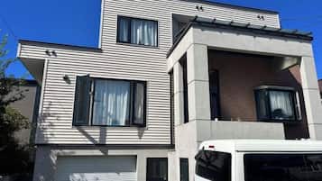 A modern two-story building with a garage door, large windows, and a vehicle parked in front.