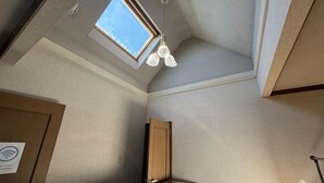 A room with a skylight, a ceiling fan, and a door with a Wi-Fi symbol. - ShareHouse (Sapporo)