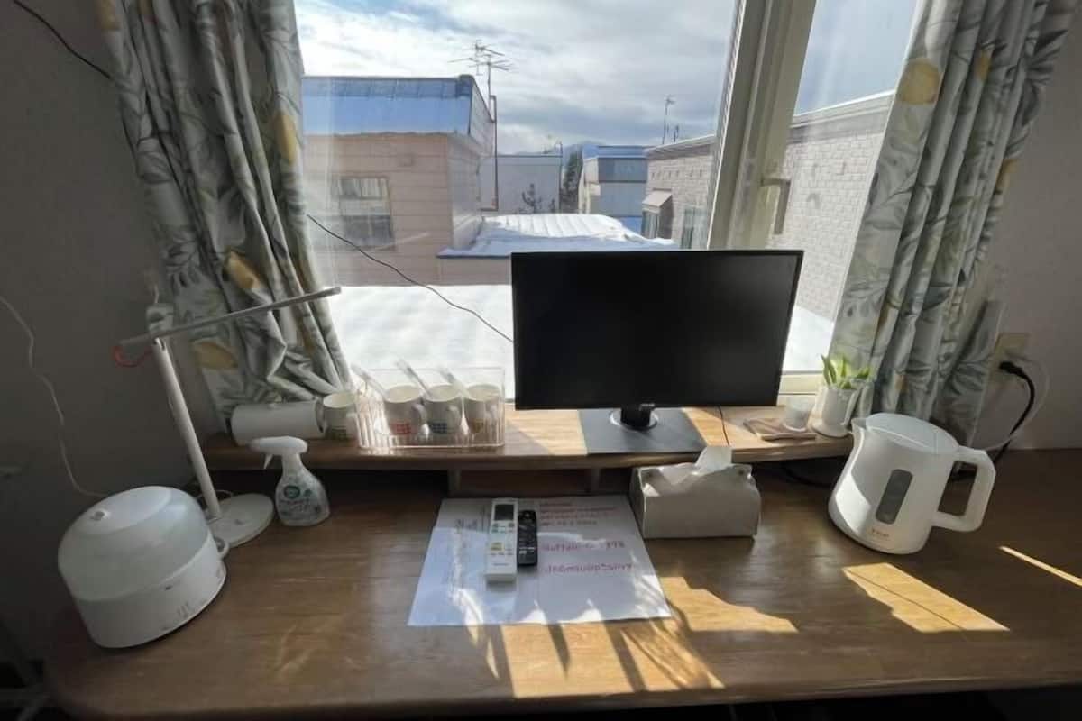 Un bureau avec un écran d’ordinateur, une lampe, une tasse, un mug et une petite plante.