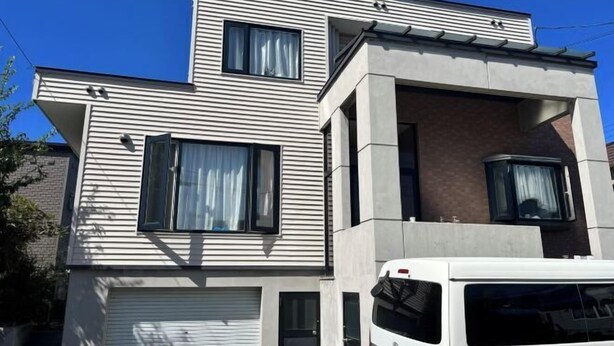 A modern two-story building with a garage door, large windows, and a white vehicle parked in front. - ShareHouse (Sapporo)