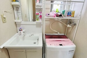 A compact bathroom with a sink, a mirror, and a small storage unit with toiletries. - ShareHouse (Sapporo)
