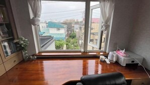 A room with a large window, a wooden desk, a black chair, and a bedside table with a lamp. - ShareHouse (Sapporo)