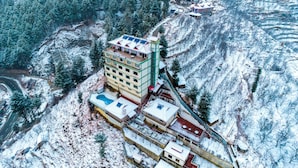A multi-story hotel with a central courtyard, surrounded by snow-covered terrain and dense forest. - Hilltop Resort, Narkanda (Theog)