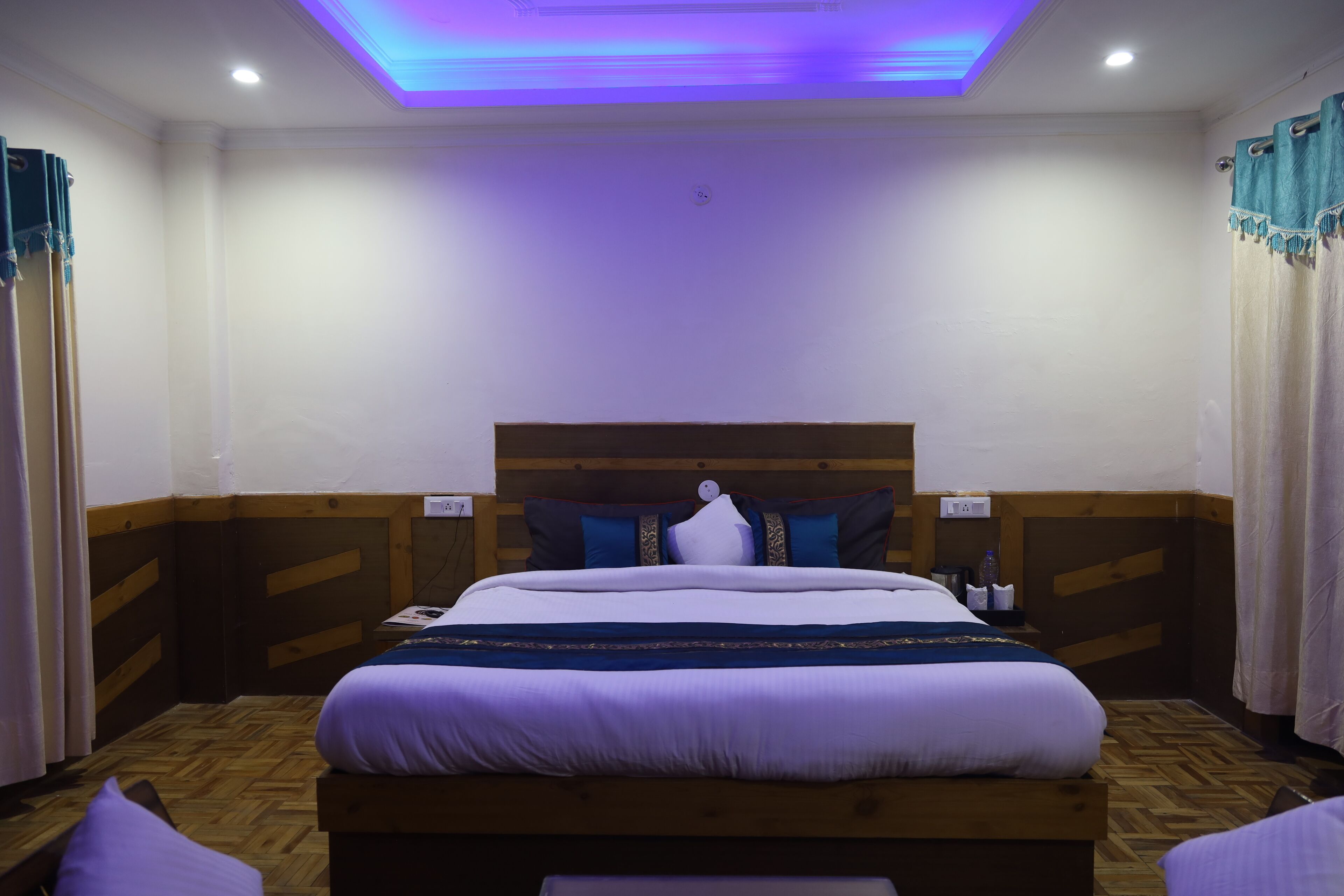 A hotel room with a large bed, wooden headboard, and a ceiling light fixture.