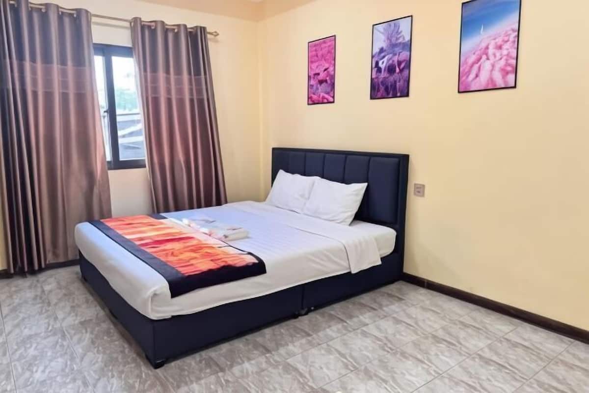 A bedroom with a bed, curtains, and three framed pictures on the wall.