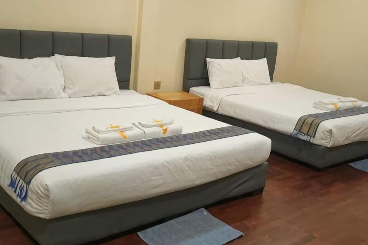 Two twin beds with grey headboards, white linens, and a blue and white striped bed runner.