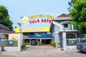 The entrance to Yula Hotel with a signboard and a gated driveway. - Yula Hotel Thatluang (Vientiane)