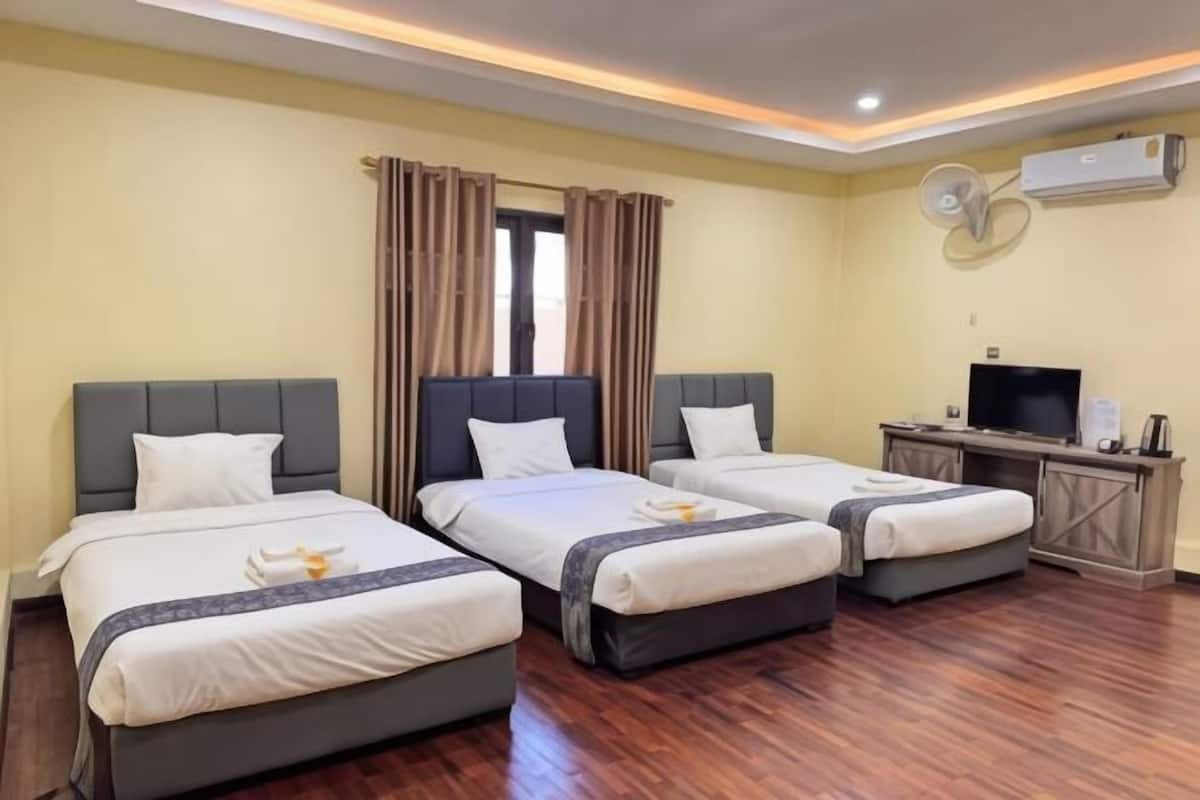 A hotel room with three beds, a TV, and an air conditioning unit.