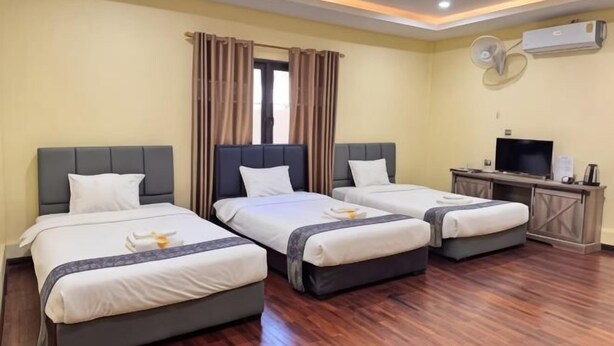 Een hotelkamer met drie bedden, een televisie en een airconditioningsysteem.