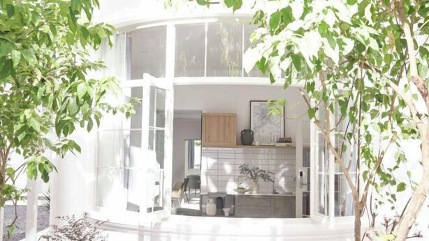A modern, white, two-story building with large windows and a curved balcony.