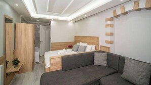A modern bedroom with a bed, a sofa, a wooden wardrobe, and a ceiling with recessed lighting. - New Life Taksim Hotel (Istanbul)