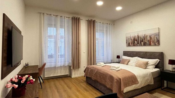 Ett modernt hotellrum med en stor säng, ett skrivbord med en stol, en platt-TV och en tavla på väggen.