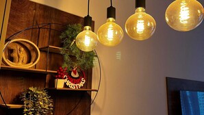 Ett rum med hyllor i trä, en juldekoration och hängande glödlampor i Edison-stil.